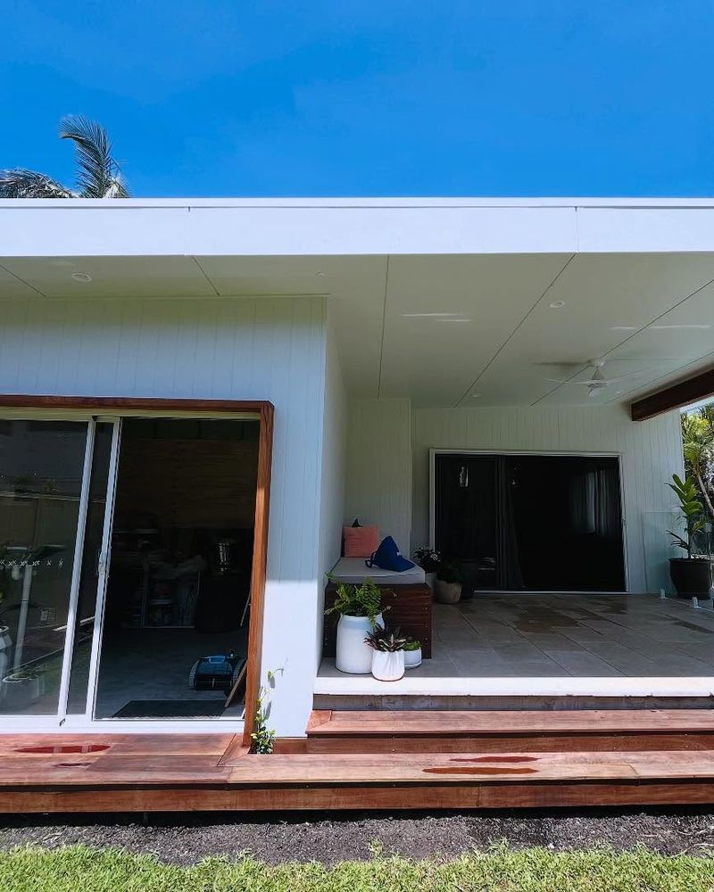 Completed pool house with sliding doors and a timber deck beside a swimming pool, Sandy Beach